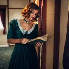 Kobieta w sukience w stylu lat 40. z koronkowym kołnierzykiem czyta książkę w zabytkowym wnętrzu.