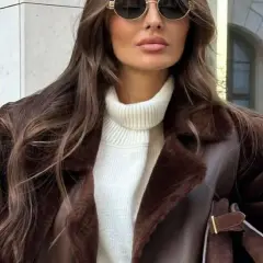 Elegancka kobieta w brązowym, futrzanym korzuszek i białym golfie, nosząca okulary przeciwsłoneczne.