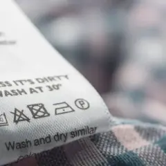 Metka z instrukcją prania: "UNLESS IT'S DIRTY WASH AT 30°". Podpowiada, z jakich materiałów kupować ubrania, by służyły dłużej.