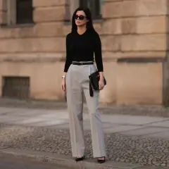 Eleganckie stylizacje na urodziny: czarna bluzka, szare spodnie z wysokim stanem, pasek i kopertówka. Idealny zestaw na świętowanie!