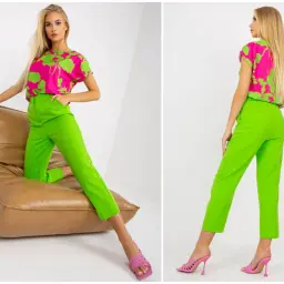 Modelka prezentuje stylizację: jaka bluzka do zielonych spodni? Neonowa bluzka z wzorem i dopasowane zielone spodnie.