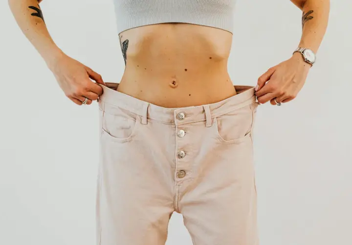 Kobieta pokazuje, jak bardzo luźne są jej spodnie. Kiedyś nosiła rozmiar 5XL, a teraz są jej za duże.