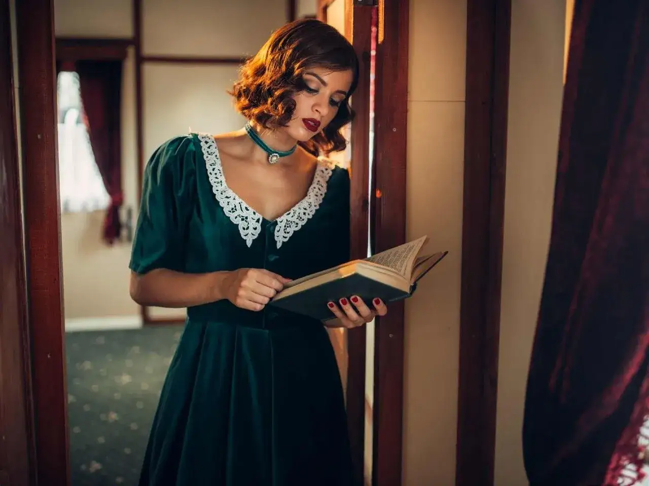 Elegancka kobieta w sukni w stylu lat 40. czyta książkę, zanurzona w historii.